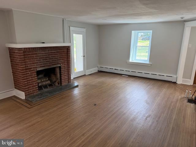 639 Old Airport Rd, Douglassville, PA 19518 - unfurnished living room featuring a baseboard heating unit, healthy amount of natural light, a fireplace, and wood finished floors