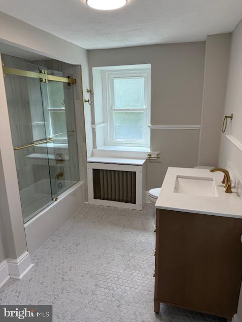 639 Old Airport Rd, Douglassville, PA 19518 - bathroom with vanity, enclosed tub / shower combo, toilet, baseboards, and radiator