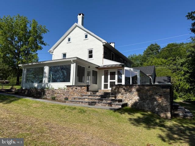 639 Old Airport Rd, Douglassville, PA 19518 - rear view of house featuring a sunroom, a chimney, a yard, stucco siding, and stone siding