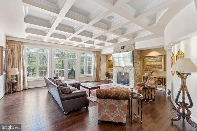 living room with beamed ceiling, coffered ceiling, dark wood finished floors, and a stone fireplace