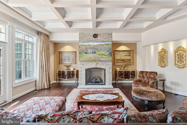 living room featuring baseboards, coffered ceiling, hardwood / wood-style floors, and a stone fireplace