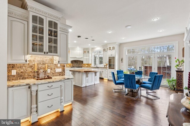 interior space featuring glass insert cabinets, tasteful backsplash, a kitchen island, and recessed lighting