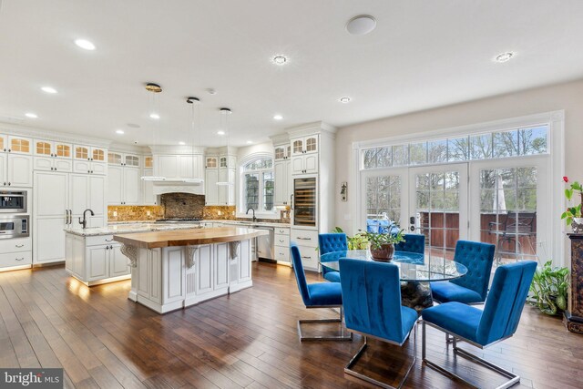 kitchen with appliances with stainless steel finishes, a center island, a wealth of natural light, wine cooler, and butcher block counters