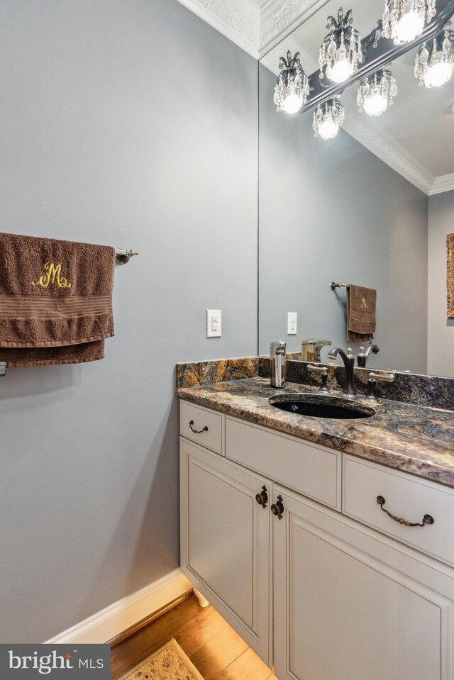 bathroom featuring crown molding, baseboards, wood finished floors, and vanity