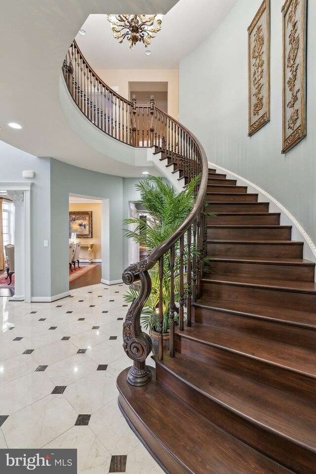 staircase featuring recessed lighting, baseboards, a notable chandelier, and a towering ceiling