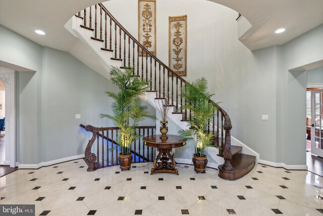 foyer with arched walkways, tile patterned floors, and baseboards