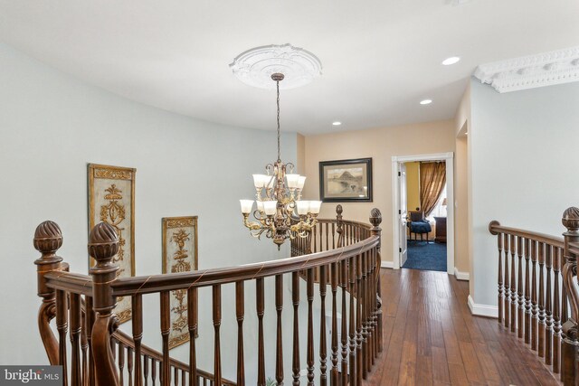 corridor with recessed lighting, a notable chandelier, dark wood-style flooring, and an upstairs landing