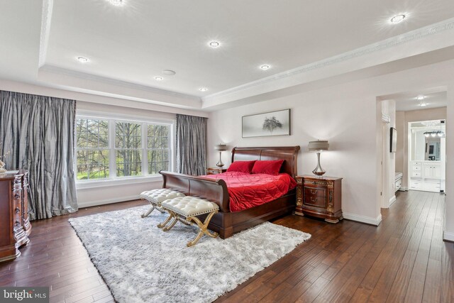 bedroom with crown molding, a raised ceiling, baseboards, and dark wood-style floors