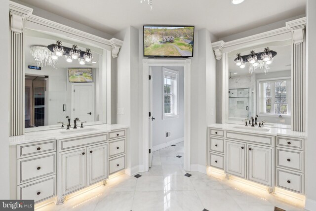 full bath featuring an inviting chandelier, a sink, baseboards, and two vanities