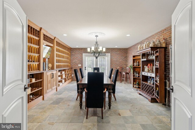 dining room with recessed lighting, stone finish flooring, brick wall, and a chandelier