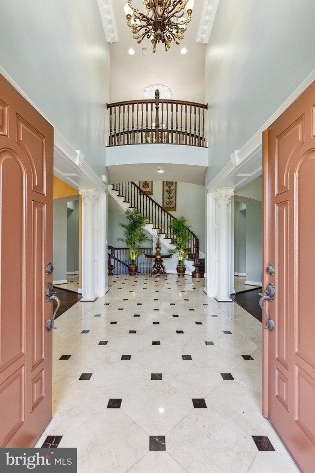 entrance foyer with ornate columns, a high ceiling, and a chandelier