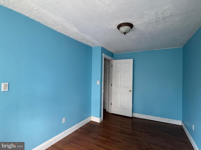 unfurnished bedroom featuring baseboards, dark wood finished floors, and a textured ceiling