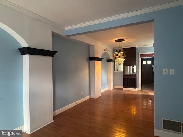 corridor featuring arched walkways, a chandelier, wood finished floors, visible vents, and ornamental molding