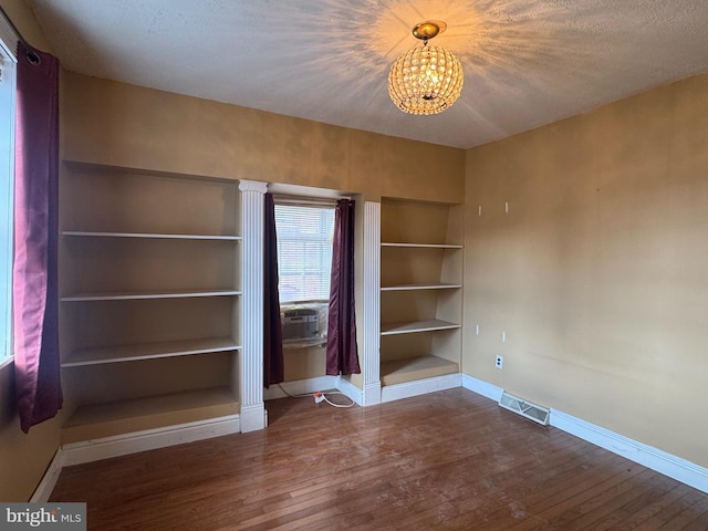 interior space featuring visible vents, built in shelves, wood finished floors, baseboards, and a chandelier