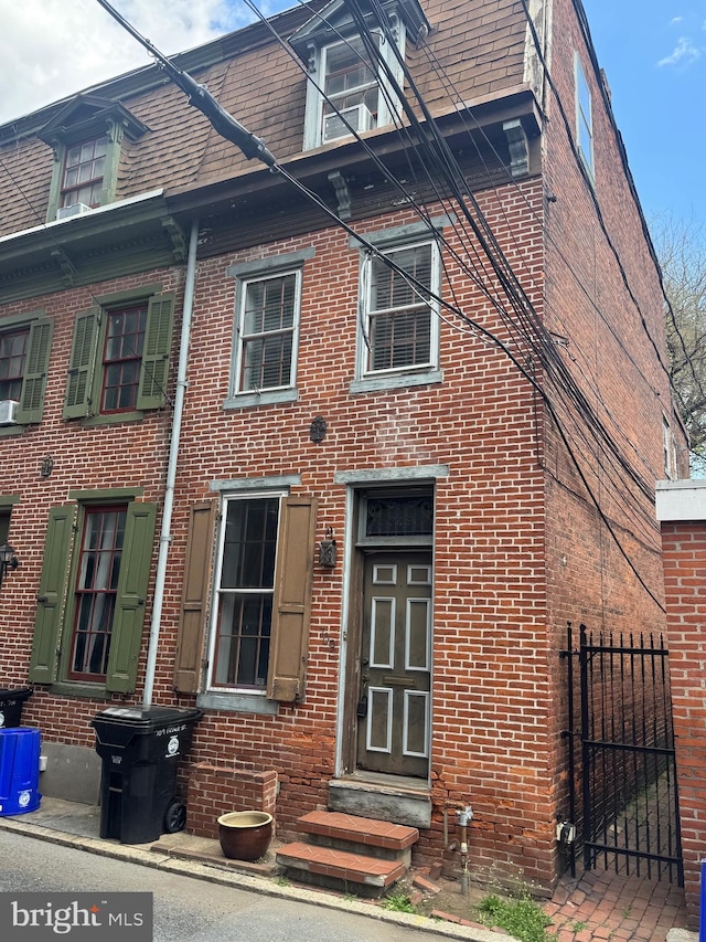 view of front of property with brick siding, fence, and entry steps
