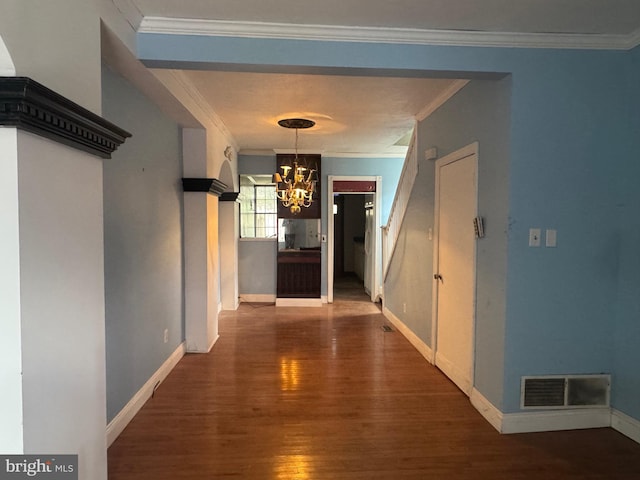 hallway featuring crown molding, visible vents, an inviting chandelier, and wood finished floors
