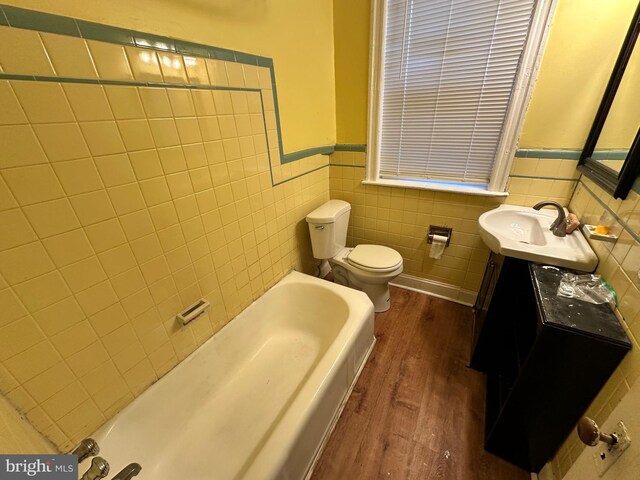 5934 Delancey St, Philadelphia, PA 19143 - bathroom with a wainscoted wall, toilet, wood finished floors, tile walls, and a bathtub