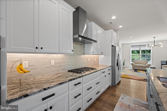 kitchen featuring dark wood-style flooring, white cabinetry, open floor plan, wall chimney exhaust hood, and appliances with stainless steel finishes
