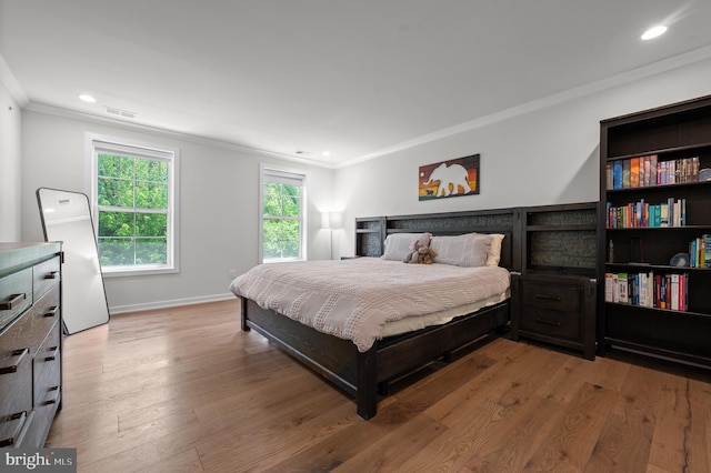 bedroom with baseboards, recessed lighting, crown molding, and wood finished floors