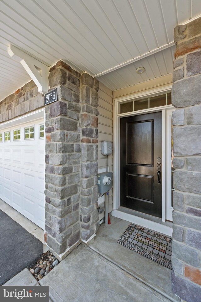 entrance to property with stone siding and a garage