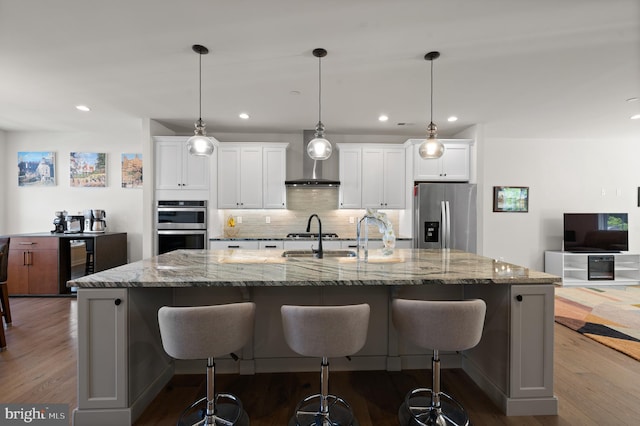 kitchen with beverage cooler, stainless steel appliances, white cabinetry, a large island with sink, and decorative backsplash