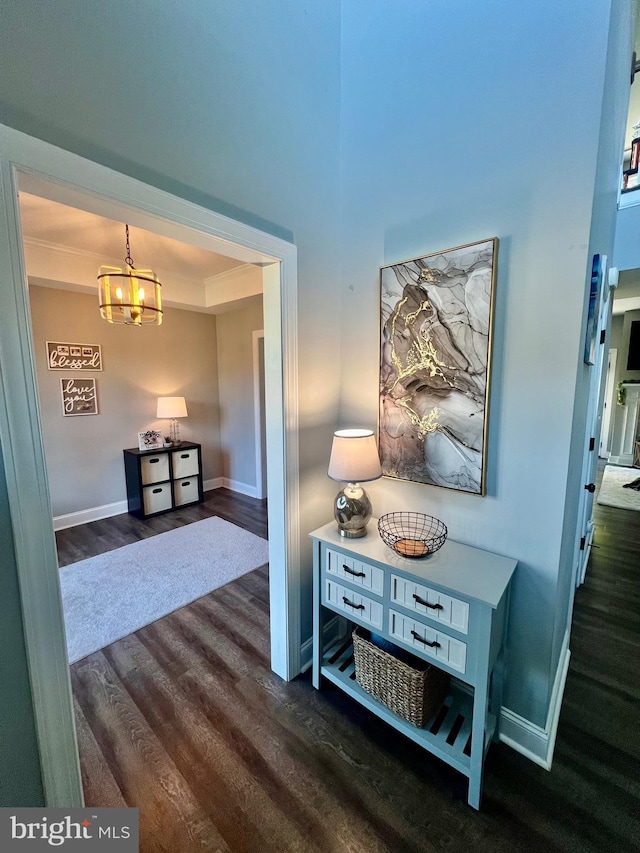 hall featuring baseboards, a notable chandelier, and dark wood finished floors