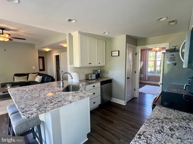 kitchen featuring baseboards, a peninsula, white cabinets, appliances with stainless steel finishes, and a sink