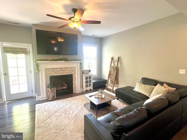 living area with a fireplace, visible vents, wood finished floors, and ceiling fan