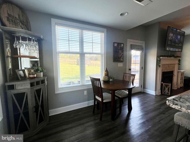 dining space featuring baseboards, a fireplace, dark wood-style floors, and plenty of natural light