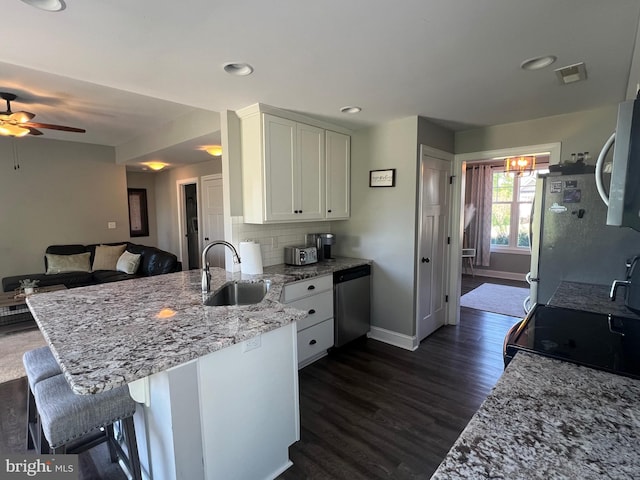 kitchen featuring baseboards, white cabinets, a sink, appliances with stainless steel finishes, and a peninsula