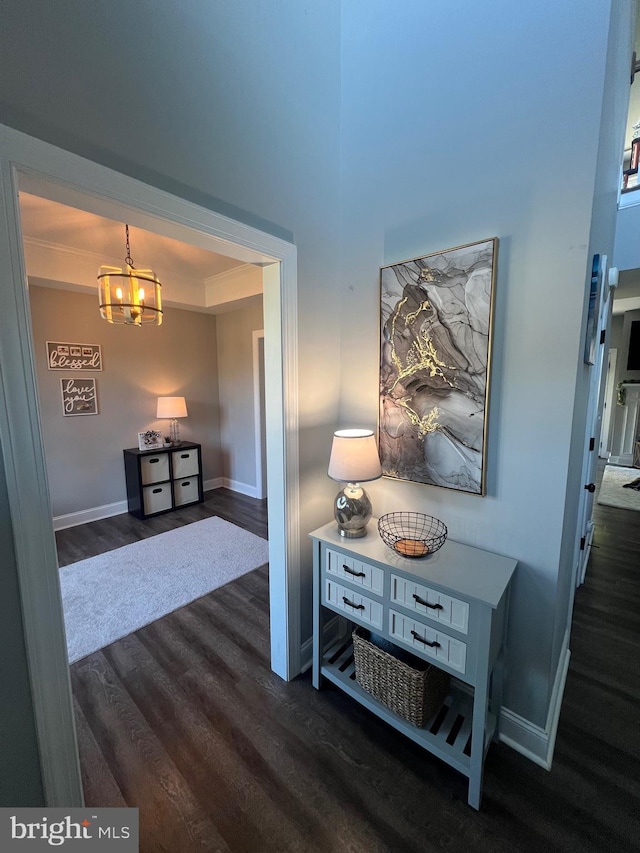 hallway featuring baseboards, a chandelier, and dark wood finished floors