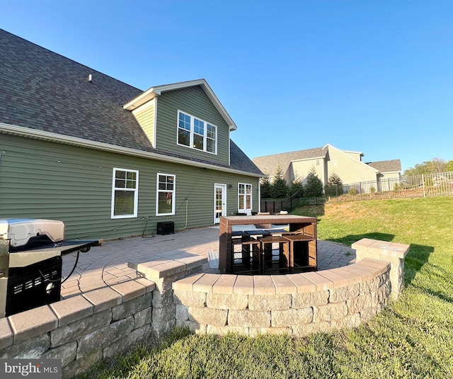 back of property featuring roof with shingles, a patio area, outdoor dining area, a yard, and fence