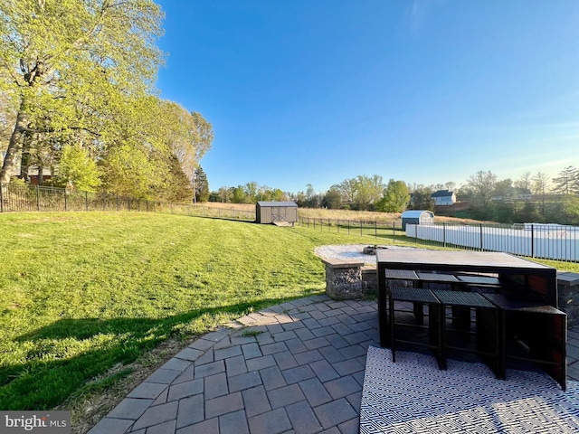 view of patio featuring an outbuilding, a fenced backyard, outdoor dining area, and a storage unit