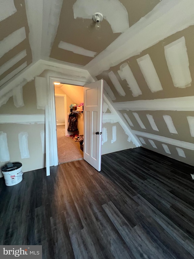 additional living space featuring dark wood-type flooring and lofted ceiling