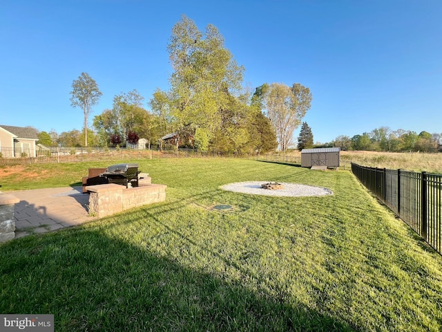 view of yard featuring a patio, a fire pit, an outdoor structure, and fence