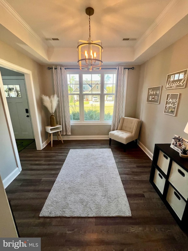 living area with a tray ceiling, an inviting chandelier, and ornamental molding