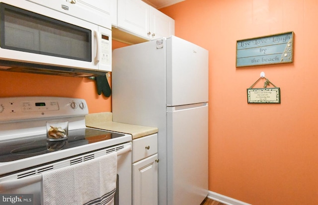 kitchen featuring light countertops, baseboards, white appliances, and white cabinetry