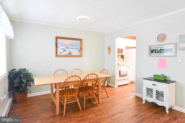 dining area with a textured ceiling, baseboards, baseboard heating, and light wood-style floors