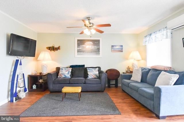 living room featuring a textured ceiling, ceiling fan, a wall mounted AC, and wood finished floors