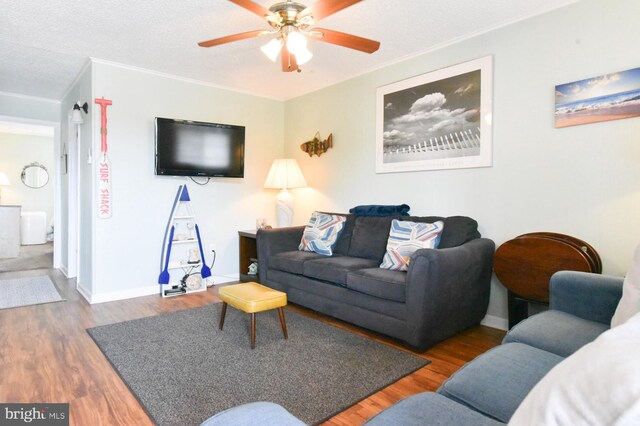 living area featuring crown molding, baseboards, a ceiling fan, and wood finished floors