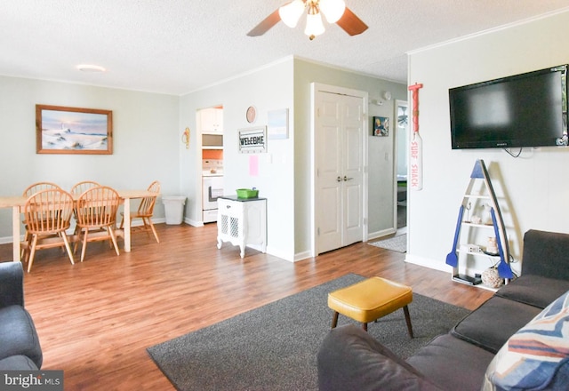 living area featuring baseboards, a textured ceiling, ceiling fan, and wood finished floors