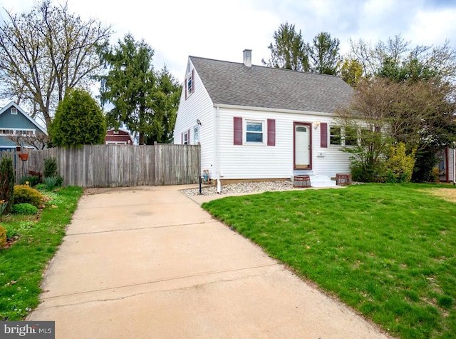 view of front of home with a shingled roof, fence, a front lawn, a chimney, and driveway