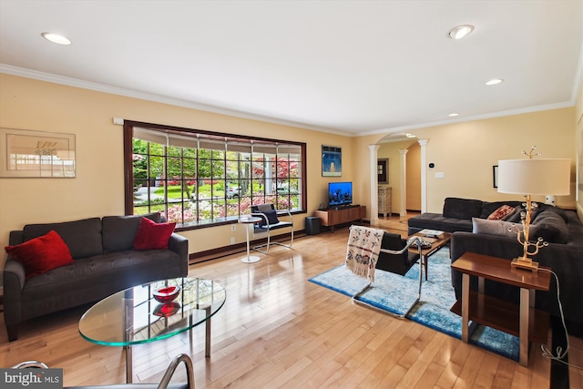 living area featuring crown molding, wood finished floors, and ornate columns