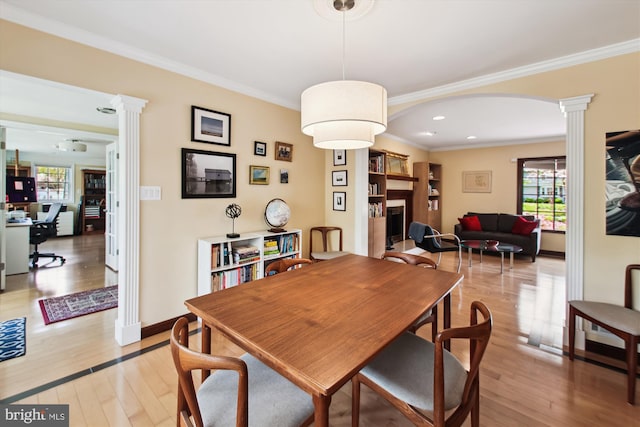 dining area with baseboards, light wood finished floors, ornate columns, and ornamental molding