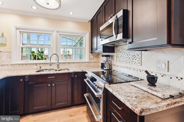 kitchen with decorative backsplash, appliances with stainless steel finishes, light stone countertops, and a sink