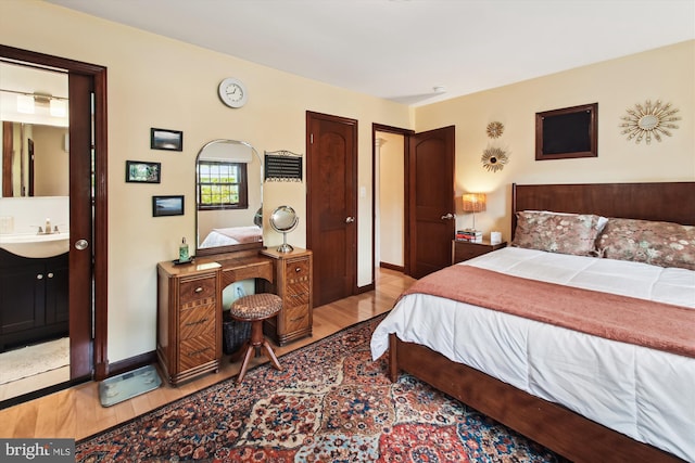 bedroom featuring baseboards, a sink, and light wood-style flooring