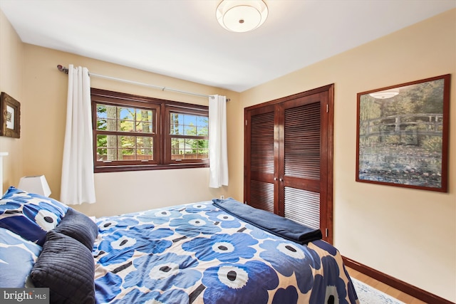 bedroom with wood finished floors, a closet, and baseboards