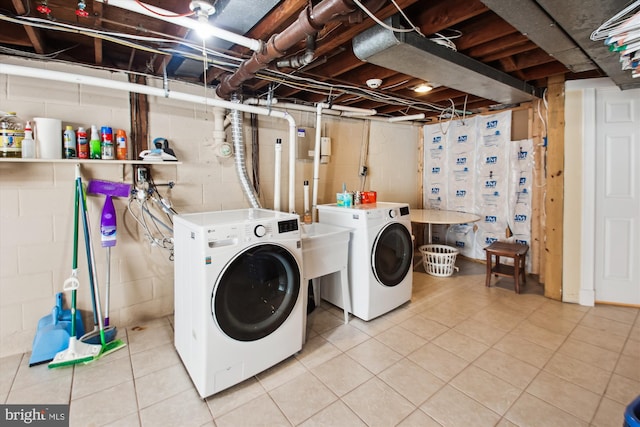 laundry room featuring concrete block wall, separate washer and dryer, tile patterned floors, and laundry area