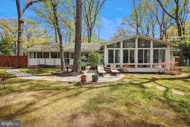 rear view of house featuring fence, a patio area, a sunroom, and a yard