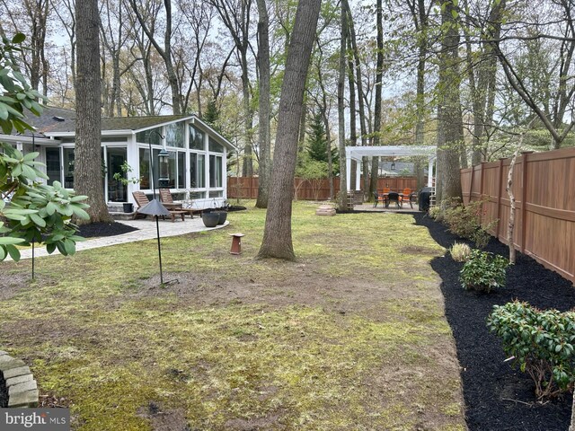 view of yard featuring a fenced backyard, a sunroom, and a patio